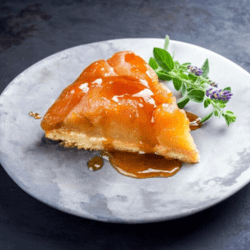 A slice of Banoffee pie drizzled with syrup and served on a white dessert plate with a plant spice to dress, based on a banoffee pie recipe from Sam's Recipe Book