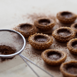 Chocolate Tarts on a table sprinkled with cocoa powder