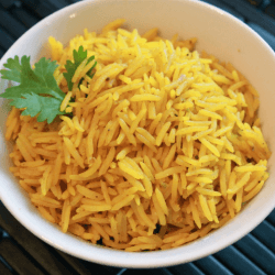 Pilau rice garnished with parsley served in a white bowl