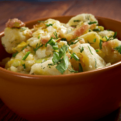 Dish of potato salad garnished with parsley served in a brown bowl