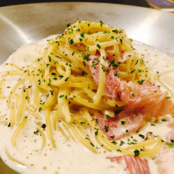 A plate of saffron spaghetti alla carbonara garnished with cheese