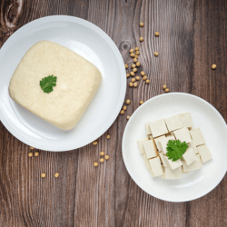 A block of tofu cheese on a white dish and another white dish with diced tofu cheese.