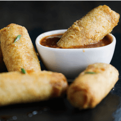 Baked egg rolls with dipping sauce in a white bowl